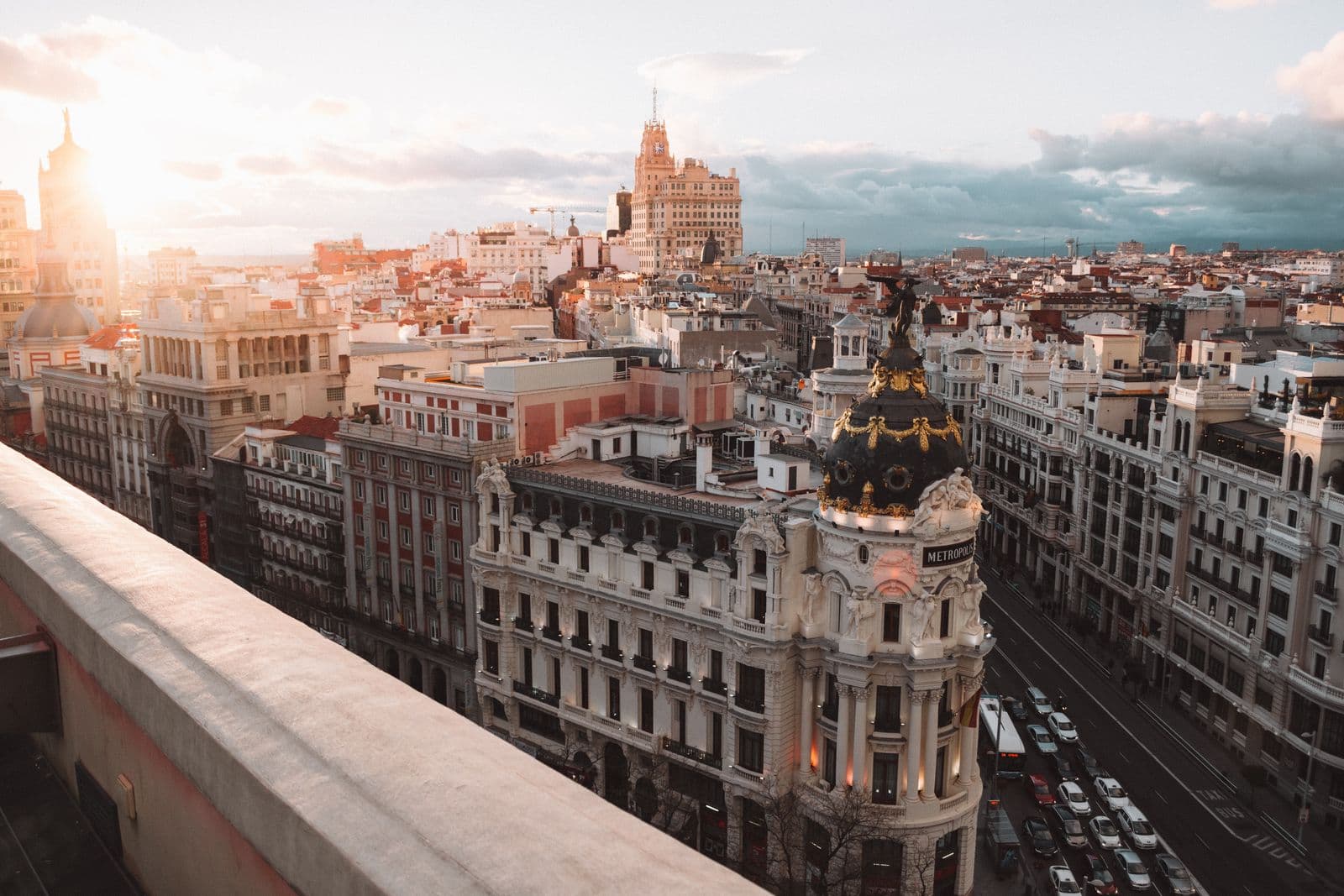 Madrid Gran Via at golden hour with the Metropolis Building dome and tiled rooftops seen from above