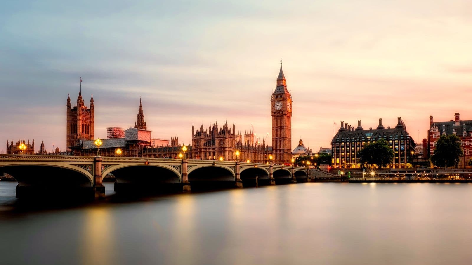 Palace of Westminster and Westminster Bridge at dusk across the Thames, streetlamps on